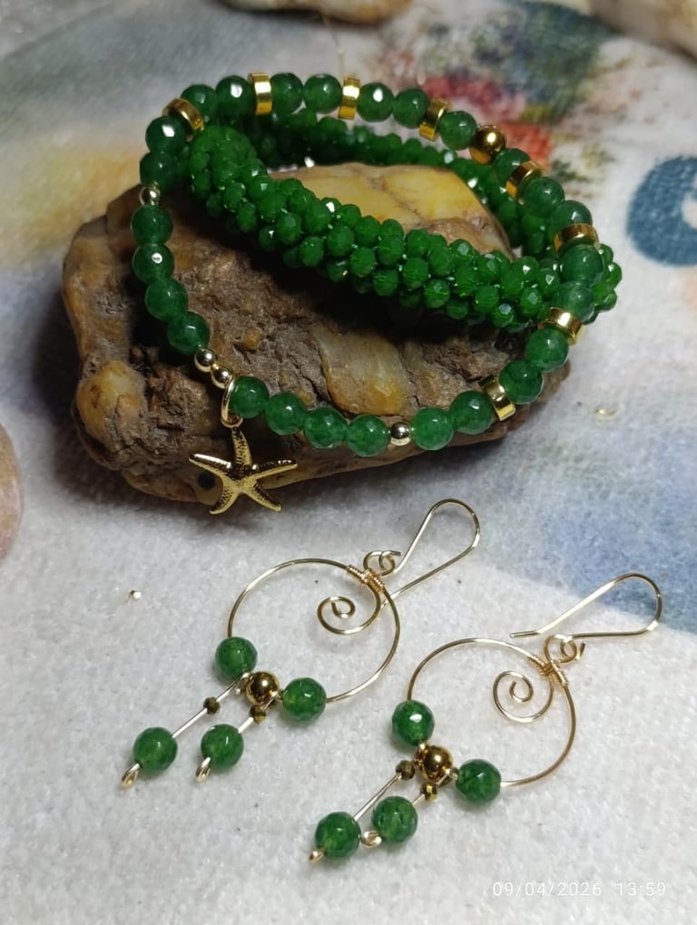 Green beaded bracelets and matching spiral earrings with gold accents on a decorative stone display