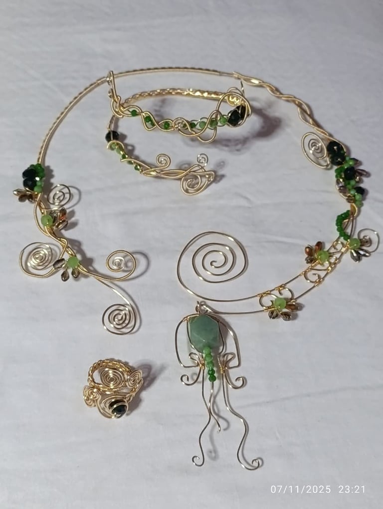 Collection of handmade wire-wrapped jewelry pieces featuring spirals, beads, and green stones on white background