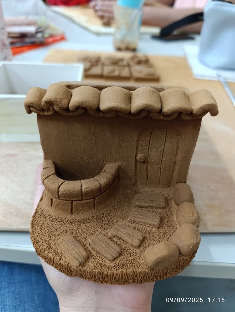 Clay sculpture of a smiling character head with large teeth and textured features, held in hand during art class