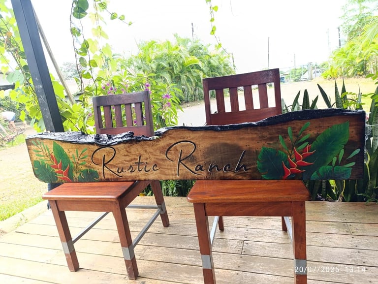 Rustic Ranches wooden bench with painted florals and lettering on a deck, flanked by wooden chairs