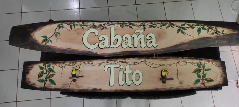 Two rustic wooden signs reading Cabana and Tito with decorative green vines and small yellow lanterns painted on them