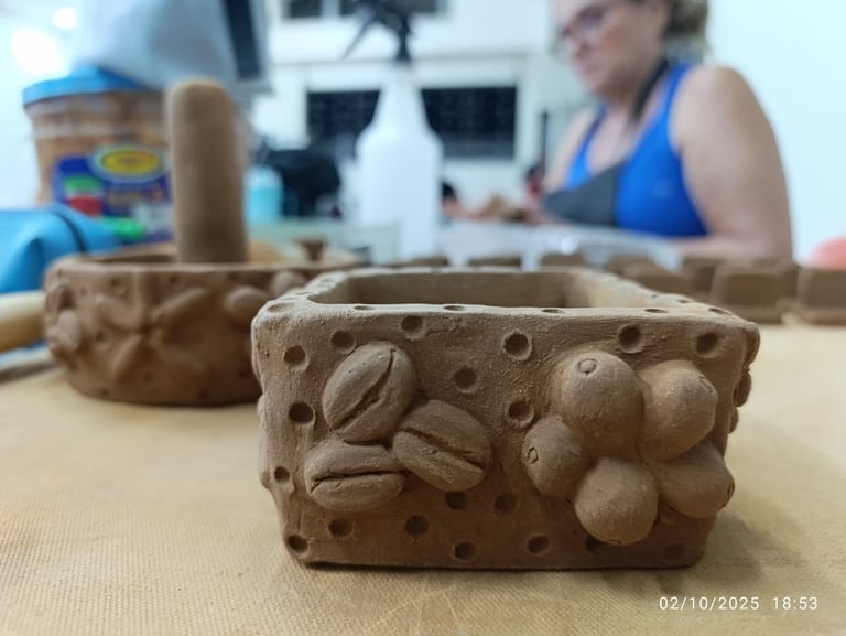 Close-up of a wooden carved butter mold with coffee bean and leaf designs, with instructor and student visible in background